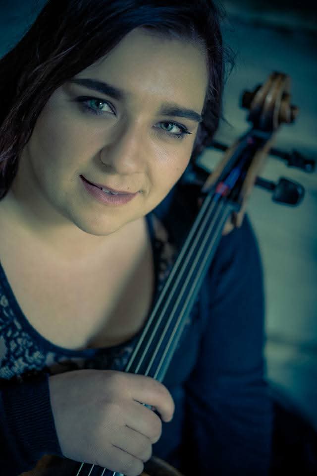 A person holding a cello  Description automatically generated